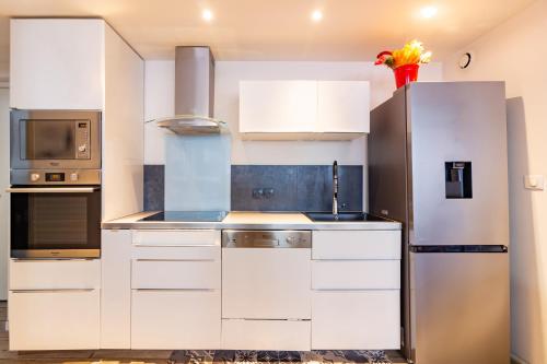 uma cozinha com armários brancos e um frigorífico de aço inoxidável em Appartement T4 central quartier Saint-Georges -Le Picomax- em Toulouse