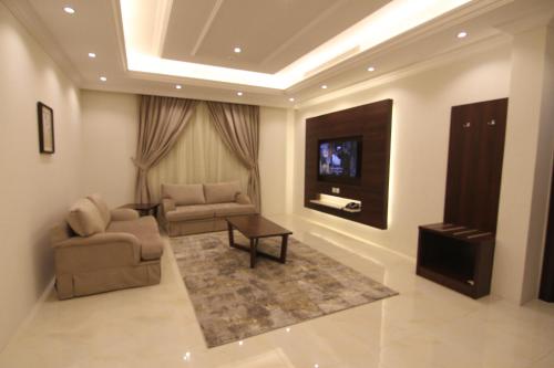 a living room with two chairs and a tv at East Diamond Serviced Apartments in Jeddah