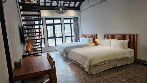璿 旅 Syuan Hotel في تاى نان: غرفة نوم بسريرين وطاولة ومكتب