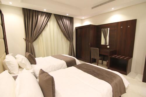 a hotel room with two beds and a desk at East Diamond Serviced Apartments in Jeddah