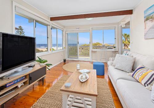 a living room with a large flat screen tv at Paradise on Jones Beach Kiama - Beachfront unit with direct beach access & views in Kiama Downs