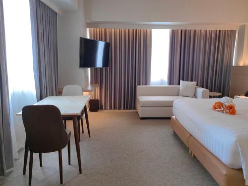 a hotel room with a bed and a couch at Brittany Hotel BGC in Manila