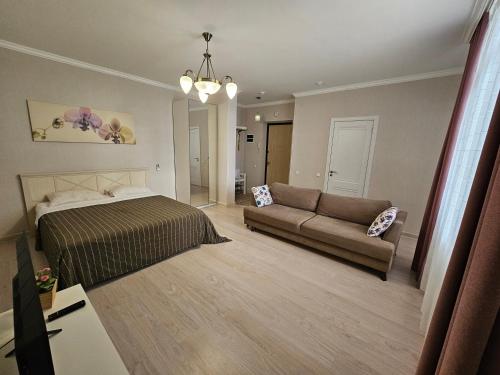 a bedroom with a bed and a couch at Ernaz Plus Apartments: Promenade Expo in Astana