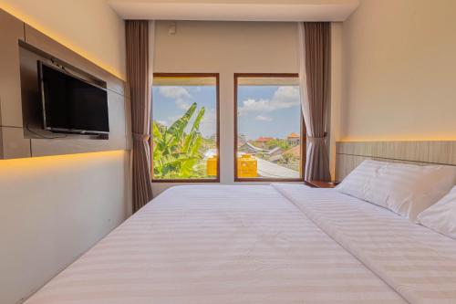 a bedroom with a large white bed and a large window at The Baliem Hotel in Jimbaran