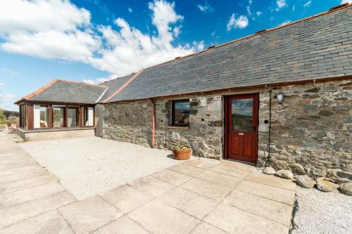 a stone building with a red door and a patio at Middle Byre at Clauchan Holiday Cottages in Gatehouse of Fleet