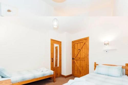 1 dormitorio con 2 camas y puerta de madera en Middle Byre, en Castle Douglas