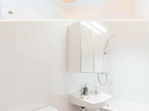 a white bathroom with a sink and a mirror at Middle Byre in Castle Douglas