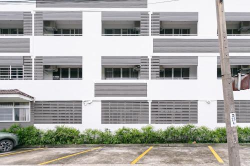 a parking lot in front of a white building at Ruan Plaisoi Apartment in Bangkok