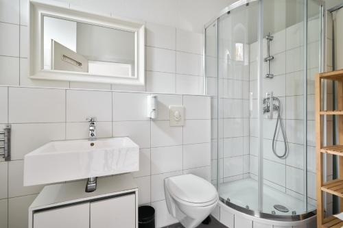a white bathroom with a sink and a shower at Cityapartment für bis zu 8 Personen in Berlin