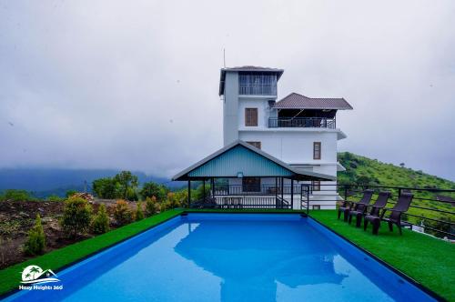 a house with a swimming pool in front of a lighthouse at Hazy Heights 360 in Munnar