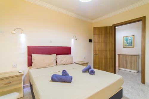 a bedroom with a large bed with blue towels on it at Pool & Sea Merill Apartments Mellieha in Mellieħa