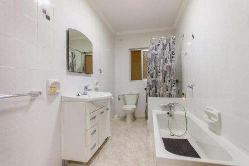 a white bathroom with a sink and a tub and a toilet at Pool & Sea Merill Apartments Mellieha in Mellieħa