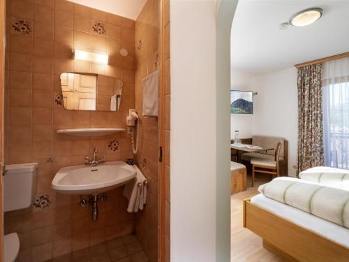een badkamer met een wastafel en een bed bij Apartment-Pension Schmiedererhof in Sankt Johann in Tirol