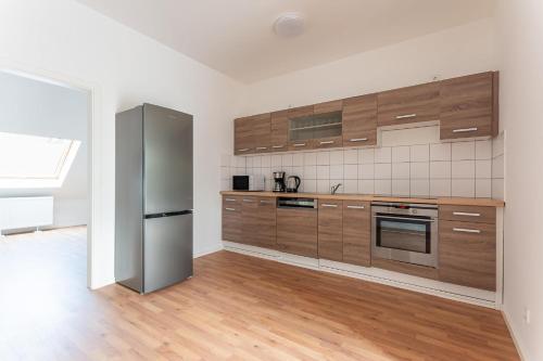 La cuisine est équipée d'armoires en bois et d'un réfrigérateur en acier inoxydable. dans l'établissement T&K Apartments - DUISBURG - Frisch renovierte 4 Zimmer Maisonetten mit Privatparkplätzen, à Duisbourg