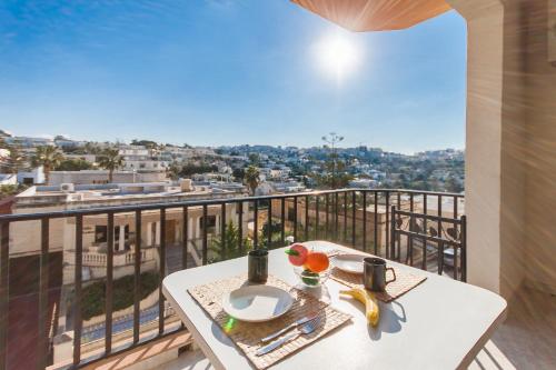 uma mesa numa varanda com vista para a cidade em Pool & Sea Merill Apartments Mellieha - Happy Rentals em Mellieħa
