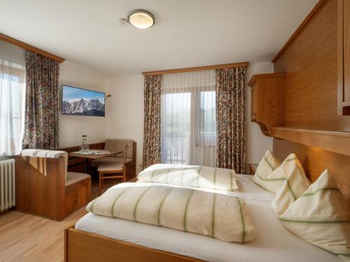 サンクト・ジョアン・イン・チロルにあるApartment-Pension Schmiedererhofのベッドとテーブルが備わるホテルルームです。