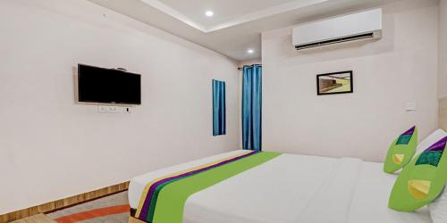 a bedroom with a bed and a flat screen tv at De Crown Luxury Hotel in Kākināda