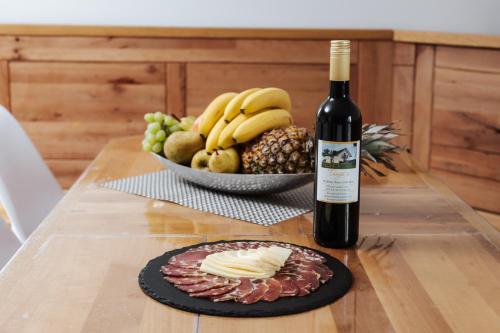 a bottle of wine and a plate of cheese and fruit at Tanja s Holiday Home in Nature with sauna and hot tub in Gorica pri Slivnici