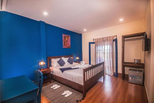 een blauwe slaapkamer met een bed en een blauwe muur bij Zen Boutique House in Luang Prabang