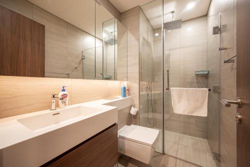 a bathroom with a sink and a glass shower at Metropole Thu Thiem Condo Apartment in Ho Chi Minh City