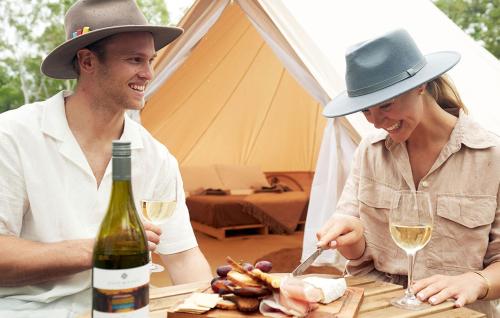 un hombre y una mujer sentados en una mesa con una botella de vino en Mount Hart Wilderness Lodge, en Wyndham