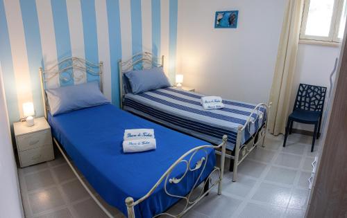 2 letti in una camera con strisce blu e bianche di Dimora Dei Turchesi a Gagliano del Capo