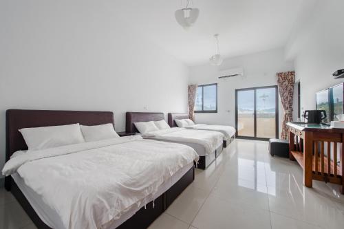 three beds in a room with white walls and windows at Quan Ming B&B in Dahu