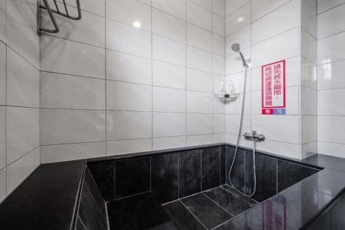 a bathroom with a shower with a black tile floor at Quan Ming B&B in Dahu