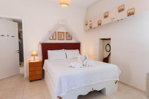 a bedroom with a white bed with a bow on it at Eirini's Traditional House in Lístaros