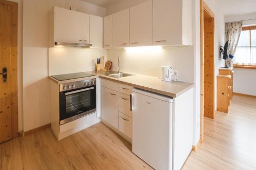 a kitchen with white cabinets and a stove top oven at Elslerhof in Dobbiaco