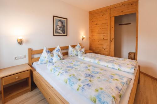 een slaapkamer met een groot bed met een houten hoofdeinde bij Elslerhof in Dobbiaco