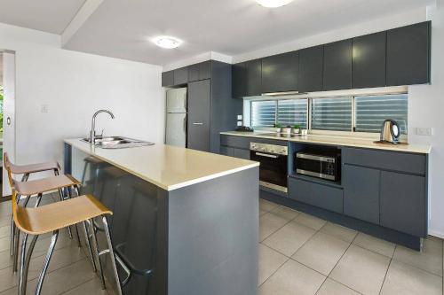 a kitchen with black cabinets and a sink and a counter at Azure Sea Whitsunday Resort in Airlie Beach