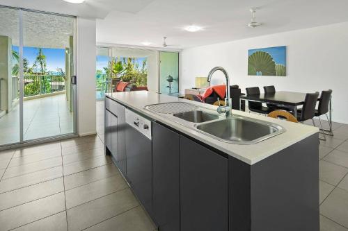 a kitchen with a sink and a living room at Azure Sea Whitsunday Resort in Airlie Beach