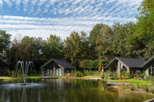 a garden with a pond and cottages at Wellness Villa with 2 Saunas, Jacuzzi & Grill Kota | 18 persons in Oirschot