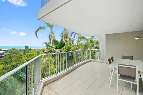 a balcony with a table and chairs and the ocean at Azure Sea Whitsunday Resort in Airlie Beach