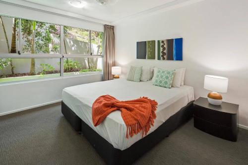 a bedroom with a large bed and two windows at Azure Sea Whitsunday Resort in Airlie Beach