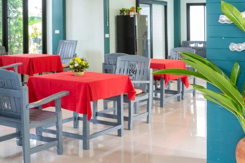 a row of tables and chairs with red table cloths at The Florist Resort in Mae Nam