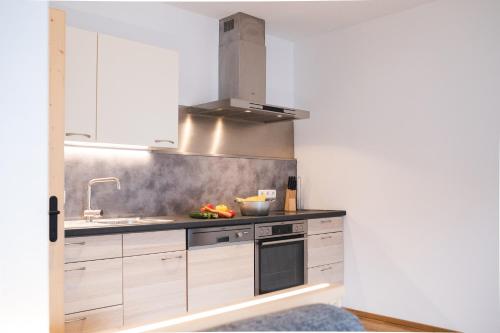 a kitchen with white cabinets and a sink at Elslerhof in Dobbiaco