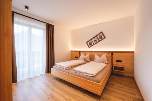 a bedroom with a bed and a large window at Elslerhof in Dobbiaco