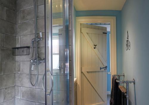a shower with a glass door in a bathroom at Boutique Fisherman's Cottage in Old Town in Scarborough