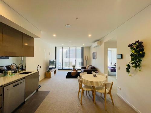 a kitchen and living room with a table and chairs at Spacious1 BR@waterfront Olympic Park_free carpark in Sydney