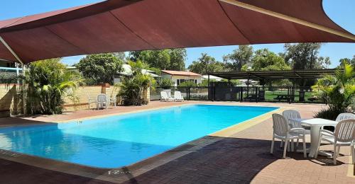 a swimming pool with a table and chairs and an umbrella at Banksia Tourist Park in Perth