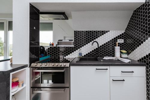 a kitchen with black and white tiles on the wall at Tanja s Holiday Home in Nature with sauna and hot tub in Gorica pri Slivnici