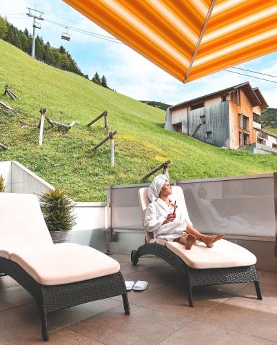 a woman sitting in a chair on a patio at Hotel TURNA Malbun in Malbun