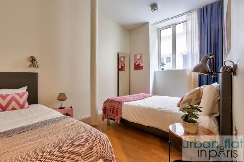 une chambre avec deux lits et une fenêtre dans l'établissement Urban Flat 77 - Sublime and Spacious Flat in Le Marais, à Paris