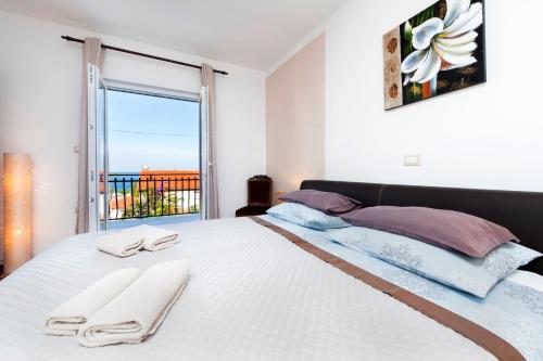 a bedroom with a large white bed with a window at Apartments & Room Anita in Rovinj