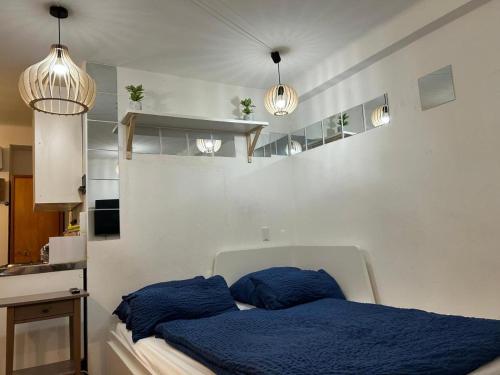 Schlafzimmer mit einem Bett mit blauer Bettwäsche und Beleuchtung in der Unterkunft Trier City Center Apartments Altstadt in Trier