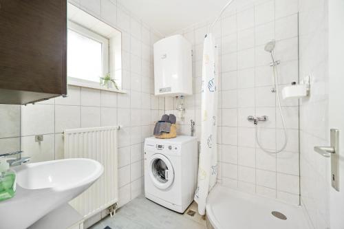 ein Badezimmer mit einer Waschmaschine und einem Waschbecken in der Unterkunft Erholung pur nahe Krankenhaus & Park mit Parkplatz in Graz