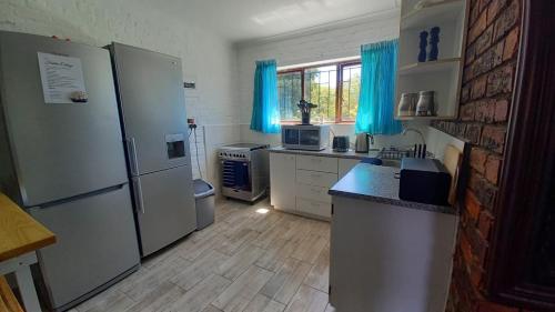 a kitchen with stainless steel appliances and blue curtains at Hidden Cottage in Bredasdorp