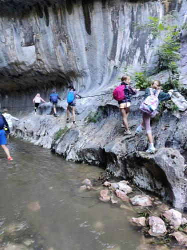 a group of people walking down a rocky hill next to a river at Natural e Simplu in Petroşani